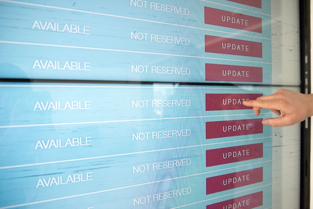 A hand interacts with a digital touchscreen interface showing availability and update options.